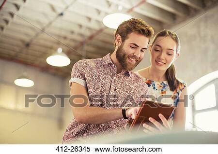 Casual business people sharing digital tablet in office View Large Photo Image Stock Photography - Casual business people sharing digital tablet in office. Fotosearch