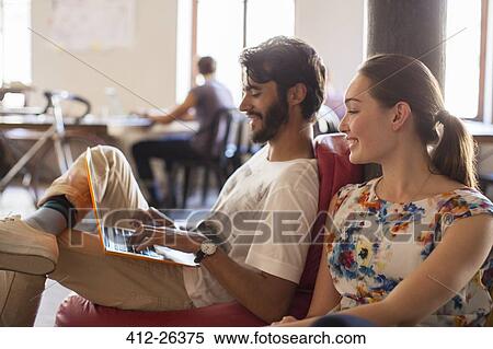Casual business people using laptop in office View Large Photo Image Stock Photography - Casual business people using laptop in office. Fotosearch