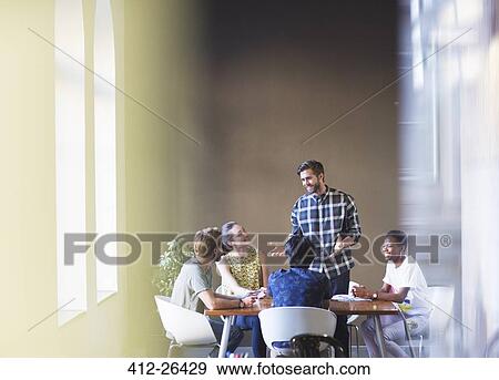 Casual businessman leading meeting at office table View Large Photo Image Stock Photo - Casual businessman leading meeting at office table. Fotosearch