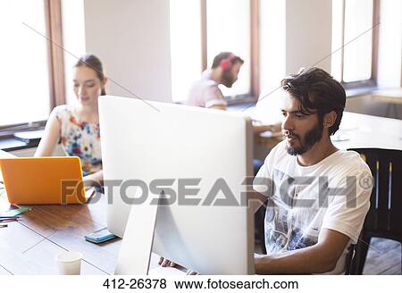 Casual businessman working at computer in office View Large Photo Image Stock Photo - Casual businessman working at computer in office. Fotosearch