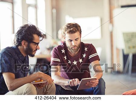 Picture - Casual businessmen using digital tablet in office. Fotosearch