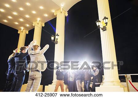 Celebrities posing with arms raised for paparazzi photographers at event View Large Photo Image Stock Photo - Celebrities posing with arms raised for paparazzi photographers at event. Fotosearch