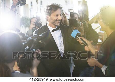 Celebrity being interviewed and photographed by paparazzi photographers at red carpet event View Large Photo Image Stock Photo - Celebrity being interviewed and photographed by paparazzi photographers at red carpet event. Fotosearch