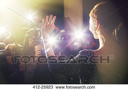 Stock Image - Celebrity waving for paparazzi photographers at event. Fotosearch