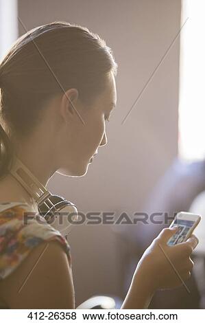 Stock Photo - Close up woman with headphones using cell phone. Fotosearch