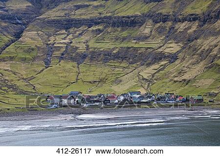 Stock Photo - "Coastal village below green cliffs, Tjornuvik, Faroe Islands". Fotosearch
