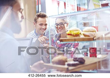 Couple choosing food at display case in cafe View Large Photo Image Stock Photography - Couple choosing food at display case in cafe. Fotosearch