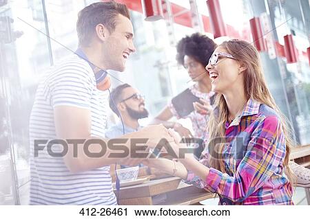 Stock Image - Couple laughing and holding hands in cafe. Fotosearch
