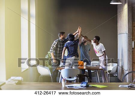 Creative business people joining hands at table in office View Large Photo Image Stock Photo - Creative business people joining hands at table in office. Fotosearch
