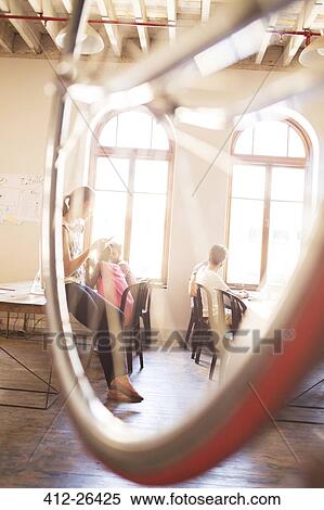 Stock Photography - Creative business people working behind bicycle wheel in office. Fotosearch