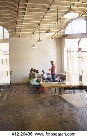 Stock Photograph - Creative businessman leading meeting in open office. Fotosearch