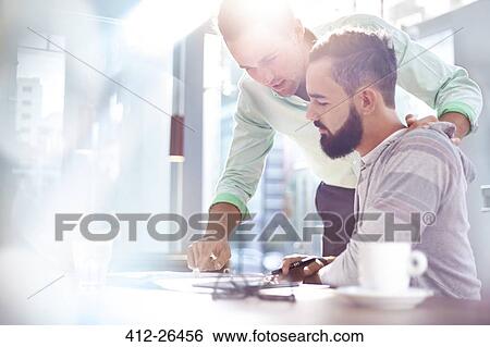 Stock Photograph - Creative businessmen reviewing paperwork. Fotosearch