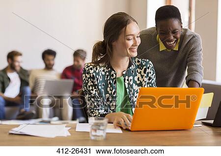 Creative businesswomen working at laptop in office View Large Photo Image Stock Image - Creative businesswomen working at laptop in office. Fotosearch