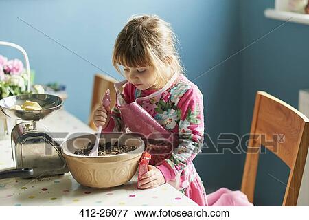 Stock Photo - Curious girl baking with mixing bowl in kitchen. Fotosearch
