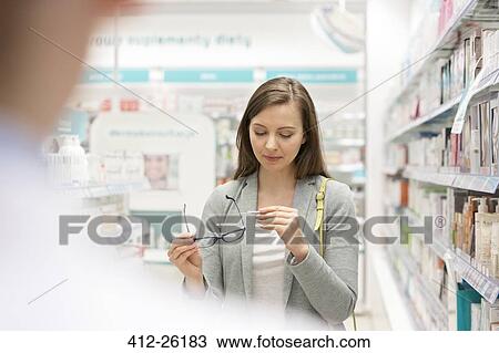 Customer looking at price tag on reading glasses in pharmacy View Large Photo Image Stock Image - Customer looking at price tag on reading glasses in pharmacy. Fotosearch