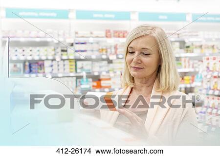 Customer reading label on box in pharmacy View Large Photo Image Picture - Customer reading label on box in pharmacy. Fotosearch