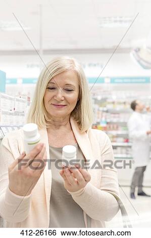Customer reading labels on bottles in pharmacy View Large Photo Image Stock Photograph - Customer reading labels on bottles in pharmacy. Fotosearch