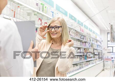 Customer trying on reading glasses in pharmacy View Large Photo Image Picture - Customer trying on reading glasses in pharmacy. Fotosearch