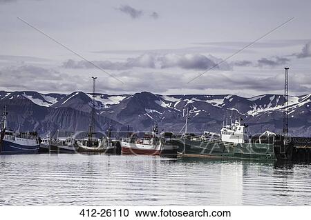 Stock Image - "Fishing boats along craggy shore, Husavik, North Iceland". Fotosearch