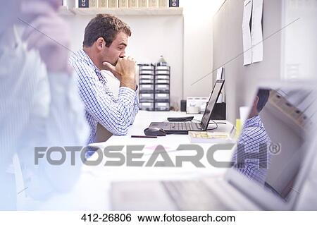 Focused architect using laptop at desk in office View Large Photo Image Stock Photograph - Focused architect using laptop at desk in office. Fotosearch