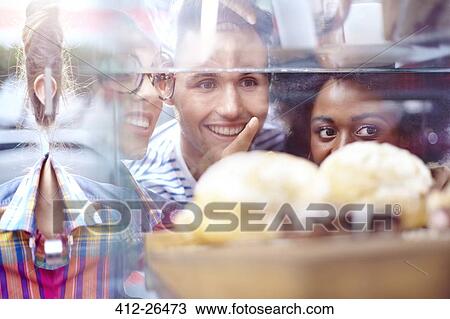 Friends pointing at desserts in display case at cafe View Large Photo Image Stock Image - Friends pointing at desserts in display case at cafe. Fotosearch