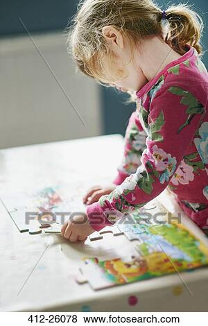 Stock Photo - Girl assembling jigsaw puzzle. Fotosearch