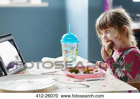 Girl eating hamburger and watching digital tablet View Large Photo Image Stock Image - Girl eating hamburger and watching digital tablet. Fotosearch