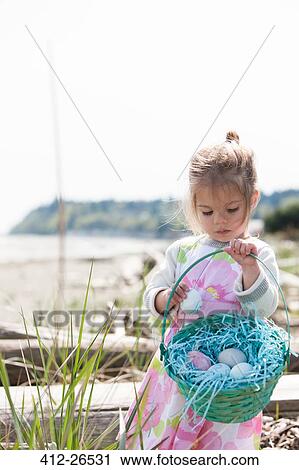 Girl gathering Easter eggs in basket on beach View Large Photo Image Stock Image - Girl gathering Easter eggs in basket on beach. Fotosearch
