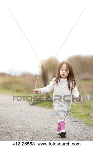 Girl in pink rain boots walking with stick View Large Photo Image Stock Image - Girl in pink rain boots walking with stick. Fotosearch