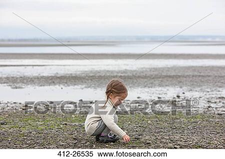 Girl picking up pebbles on beach View Large Photo Image Stock Photography - Girl picking up pebbles on beach. Fotosearch