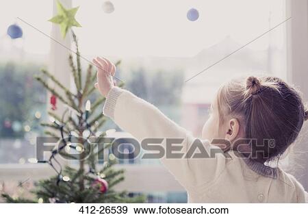 Girl reaching for start on Christmas tree View Large Photo Image Stock Photo - Girl reaching for start on Christmas tree. Fotosearch
