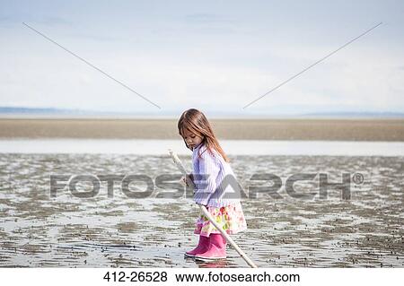 Girl with stick playing on beach View Large Photo Image Stock Photo - Girl with stick playing on beach. Fotosearch