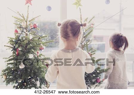 Stock Photo - Girls decorating small Christmas trees. Fotosearch