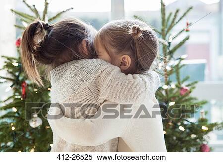 Girls hugging in front of Christmas trees View Large Photo Image Stock Photography - Girls hugging in front of Christmas trees. Fotosearch