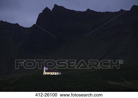 Stock Image - "Illuminated church below cliffs, Vik, Iceland". Fotosearch