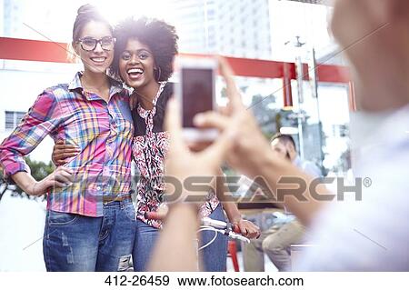 Man photographing smiling women with camera phone View Large Photo Image Stock Photo - Man photographing smiling women with camera phone. Fotosearch