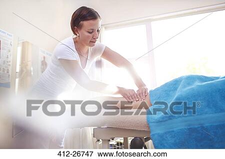 Stock Photo - Masseuse massaging woman’s leg. Fotosearch