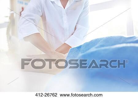 Stock Image - Masseuse rubbing woman’s leg. Fotosearch