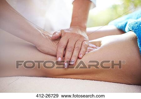 Stock Photo - Masseuse rubbing woman’s legs. Fotosearch