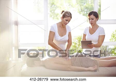 Masseuses with digital tablet massaging woman’s back View Large Photo Image Stock Photo - Masseuses with digital tablet massaging woman’s back. Fotosearch