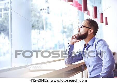 Stock Image - Pensive businessman at laptop in cafe. Fotosearch