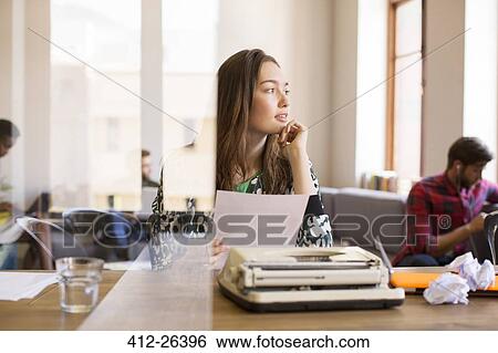 Pensive creative businesswoman with paperwork at typewriter in office View Large Photo Image Stock Photograph - Pensive creative businesswoman with paperwork at typewriter in office. Fotosearch
