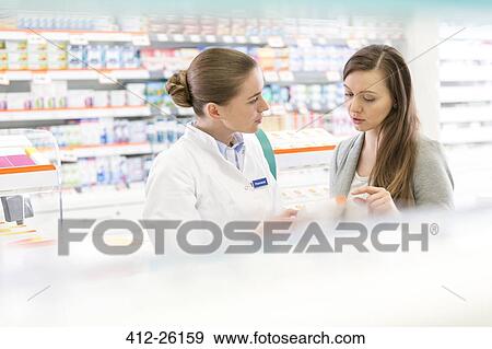 Stock Photo - Pharmacist and customer discussing prescription in pharmacy. Fotosearch