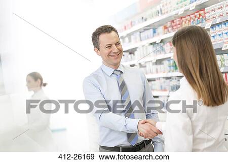 Stock Photo - Pharmacist and customer handshaking in pharmacy. Fotosearch