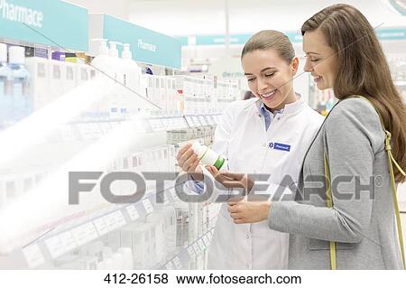 Pharmacist and customer reviewing label on bottle in pharmacy View Large Photo Image Stock Photo - Pharmacist and customer reviewing label on bottle in pharmacy. Fotosearch