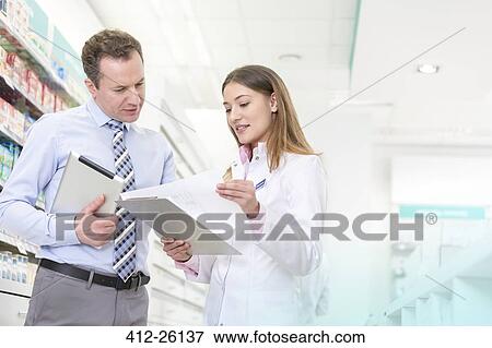 Pharmacist and manager reviewing paperwork in pharmacy View Large Photo Image Stock Photo - Pharmacist and manager reviewing paperwork in pharmacy. Fotosearch
