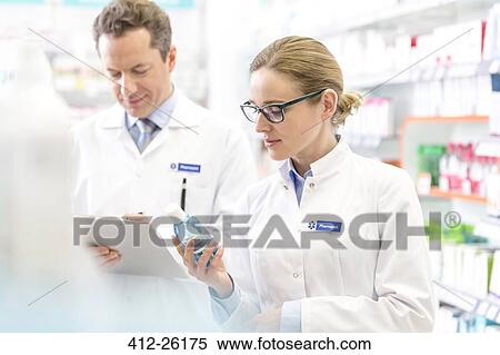 Pharmacist reading label on bottle in pharmacy View Large Photo Image Stock Photography - Pharmacist reading label on bottle in pharmacy. Fotosearch