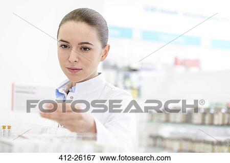 Stock Photo - Pharmacist reading label on box in pharmacy. Fotosearch