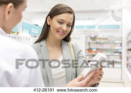 Pharmacist recommending product to customer in pharmacy View Large Photo Image Stock Image - Pharmacist recommending product to customer in pharmacy. Fotosearch