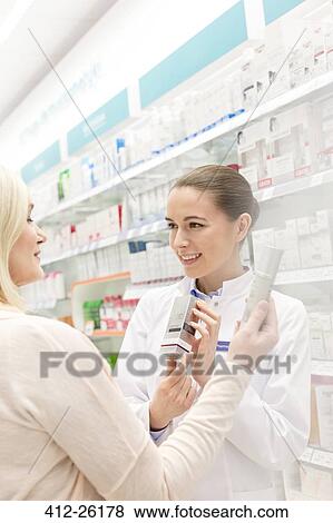 Stock Photo - Pharmacist recommending product to customer in pharmacy. Fotosearch